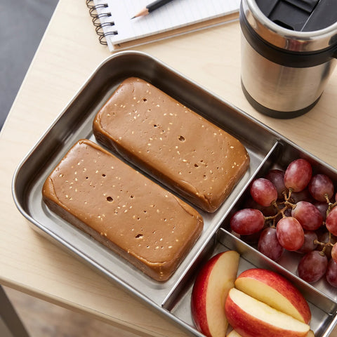 Turrón de ajonjolí en una fiambrera con fruta y un termo de café